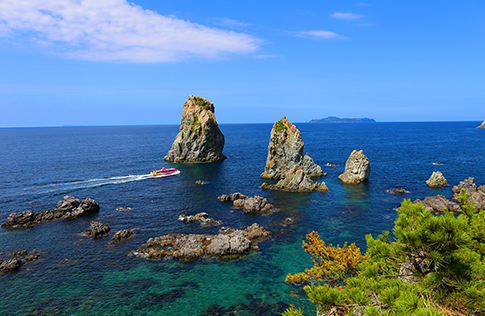 青海島の海岸線を進む観光汽船の写真