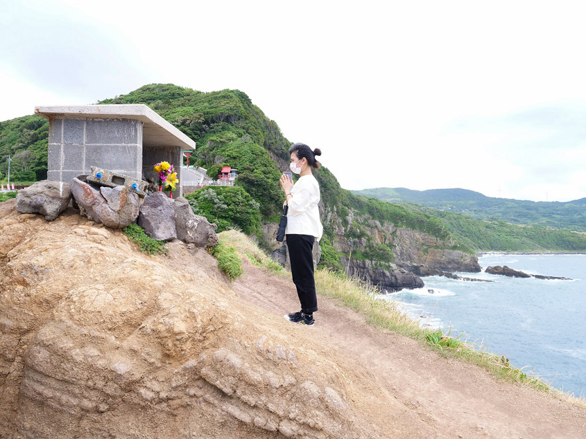 「竜宮の潮吹」の岩場にたたずむお地蔵さんとそれを拝むヒィエンさんの写真