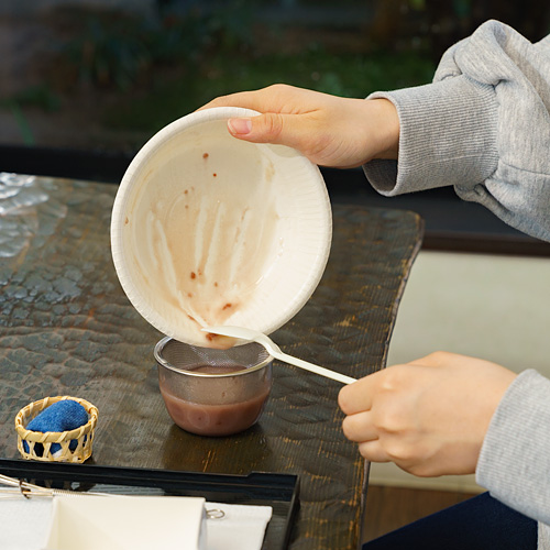 生地を茶こしがセットされたカップに移す様子の写真