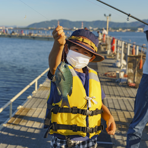 子どもが魚を持っている様子の写真